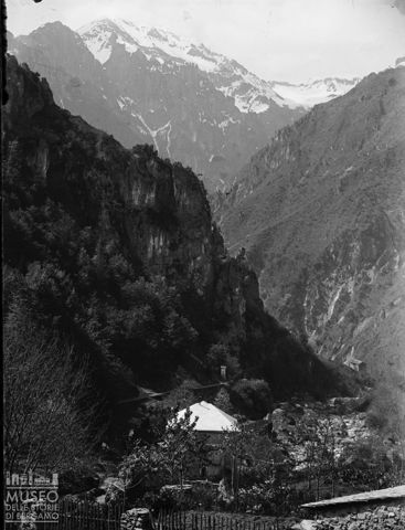 Alta Valle Brambana. Veduta panoramica con gola e casa sulla riva di un torrente