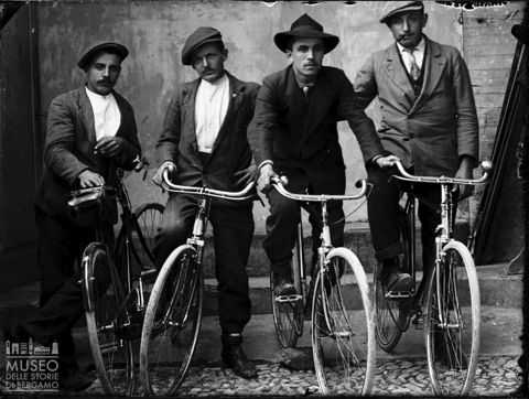 Piazza Brembana. Ritratto di quattro uomini in bicicletta