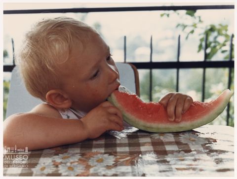 Bambina che mangia una fetta di anguria