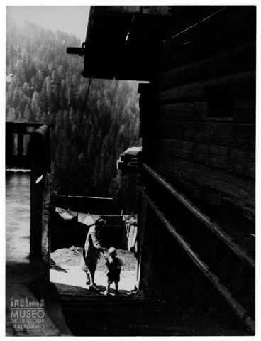 Donna e bambino ai piedi della scala di una casa di montagna