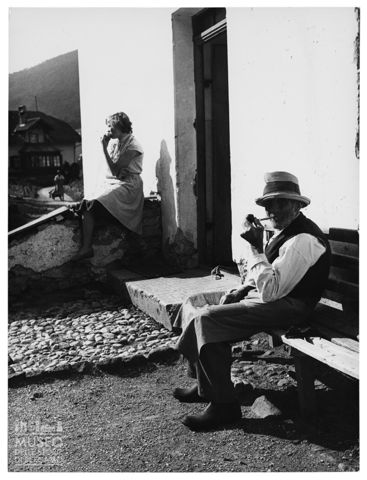 Anziano e giovane donna all'esterno di una casa di montagna