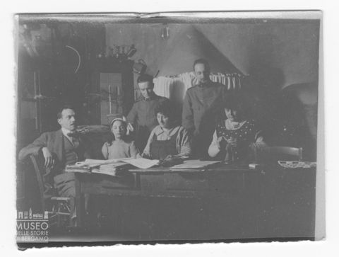 Ritratto di una bambina, due donne e tre uomini attorno ad un tavolo