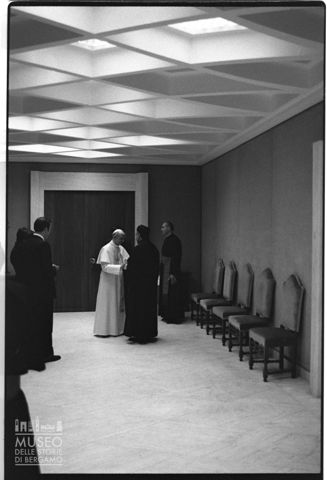 Paolo VI si intrattiene con un prelato in un corridoio dell'Aula Paolo VI