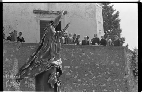 Ritratto di Floriano Bodini, Mons. Pasquale Macchi e Giulio Andreotti e altre persone affacciati a una terrazza davanti al Monumento a Paolo VI