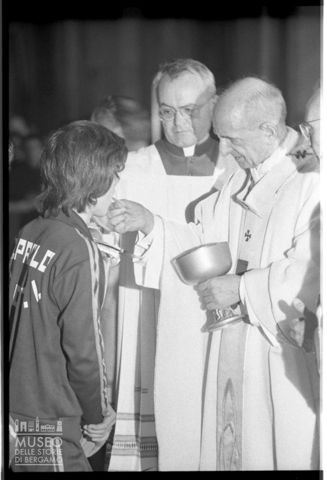 Paolo VI distribuisce l'eucarestia a un giovane atleta