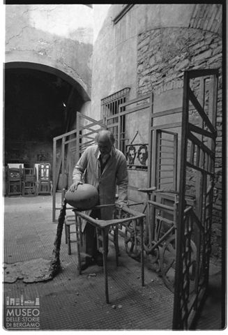 Ritratto di Sandro Angelini nella corte interna di Casa Angelini con la scultura 