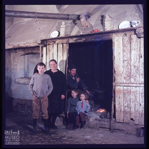 Ritratto di una famiglia davanti al camino in una casa della Val Cavallina