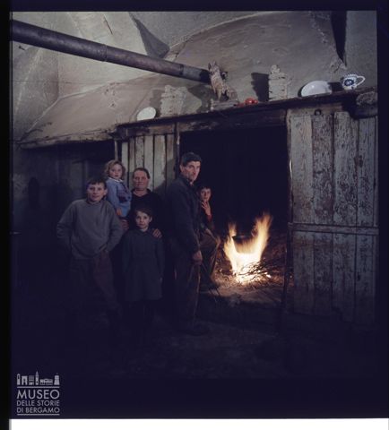 Ritratto di una famiglia davanti al camino in una casa della Val Cavallina