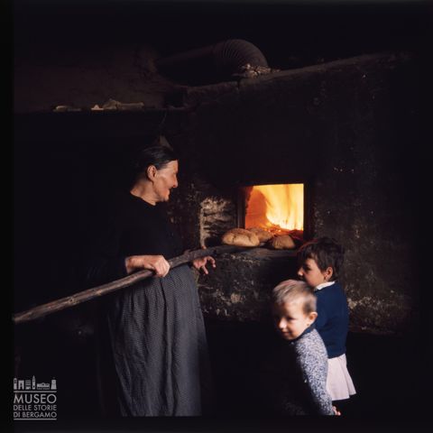 Una donna che sforna pani in un antico forno di Corteno Golgi