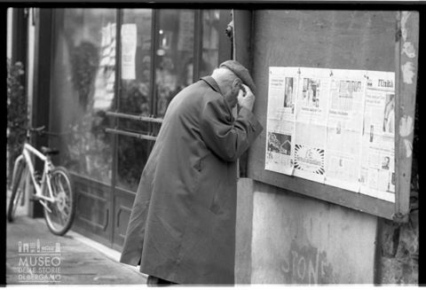 Anziano che legge a un'edicola