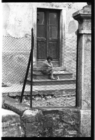 Bambino seduto che legge in Val Gandino