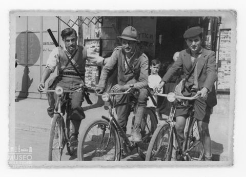 Ritratto di tre giovani in bicicletta con un fucile sulle spalle