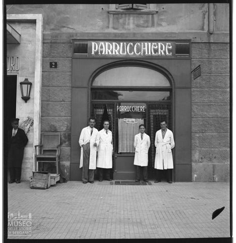 Parrucchieri in camice bianco all'esterno del loro negozio