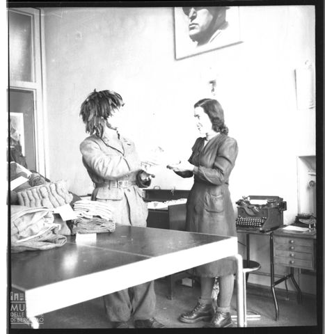 Donna consegna maglieria ad un bersagliere