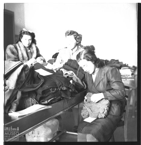 Donne al lavoro per gli indumenti dei combattenti