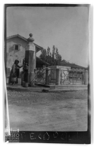 Ritratto di una donna che riempie dei secchi di acqua alla fontana