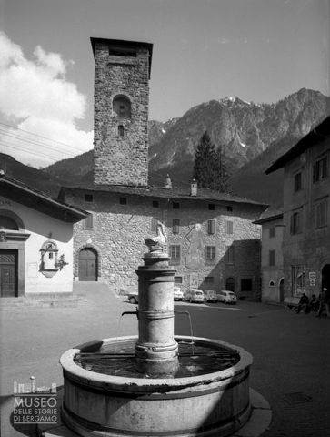 Piazza con fontana, torre e chiesa