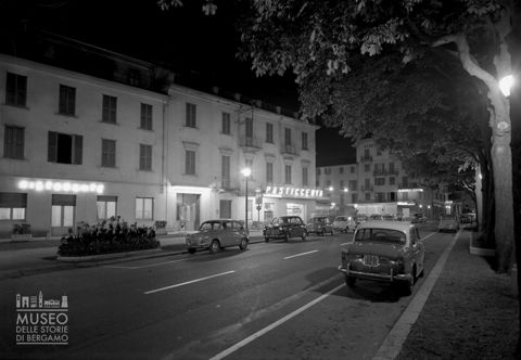 Viale con auto e locali, ripresa notturna