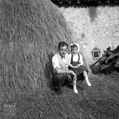 Uomo con bambina presso un covone
